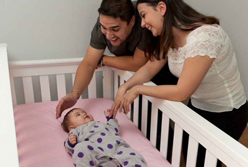 parents smiling at baby in crib