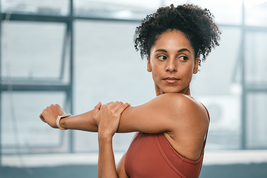 A woman with a red top stretching her arm.